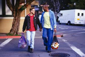 Gay couple walking through gay village carrying groceries