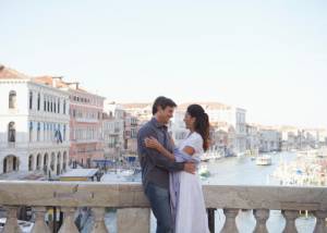 Italy, Venice, honeymoon couple embracing on bridge over canal, smiling
